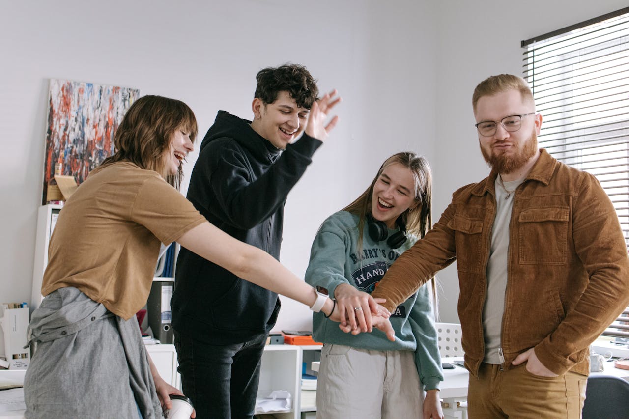 portfolio-01 A group of cheerful young colleagues celebrating with a team hand stack indoors.